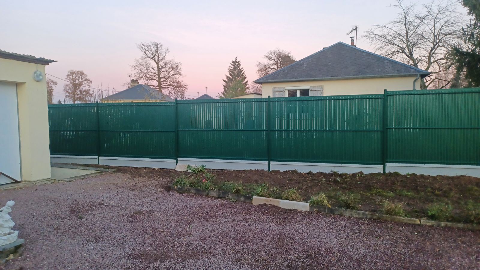 Installation d'une clôture occultante avec dalles de soubassement en béton gris en remplacement d'une haie à Brionne (27800)